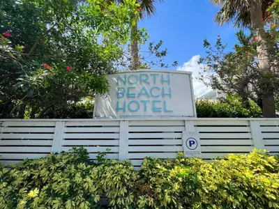 a sign for a north beach hotel behind a fence at North Beach Hotel in Fort Lauderdale