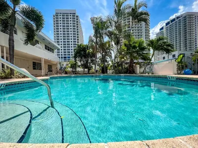 a swimming pool with palm trees and buildings at North Beach Hotel in Fort Lauderdale