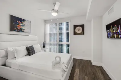 a white bedroom with a bed with a swan on it at Comfort and Convenience 2BR Unit with Free Parking in Miami