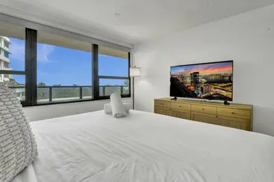 a bedroom with a large white bed and a flat screen tv at Beautiful Oceanview Condo with Beach Service 504 in Miami Beach