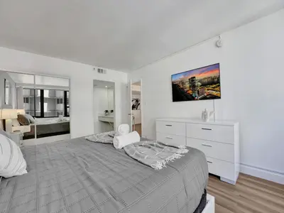 a white bedroom with a large bed and a bathroom at Luxury Beach Condo with Exclusive Resort Amenities 1016 in Miami Beach