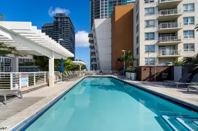 a swimming pool with chairs and a building at 1BR Miami Retreat with BBQ, Pool, & Skyline Views in Miami