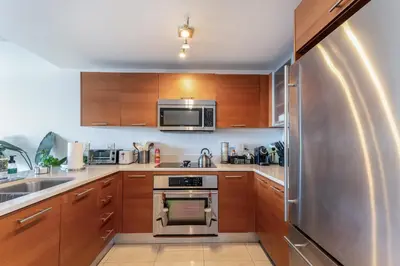 a kitchen with wooden cabinets and a stainless steel refrigerator at 1BR Miami Retreat with BBQ, Pool, & Skyline Views in Miami
