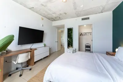 a bedroom with a bed and a tv on the wall at 1BR Miami Retreat with BBQ, Pool, & Skyline Views in Miami