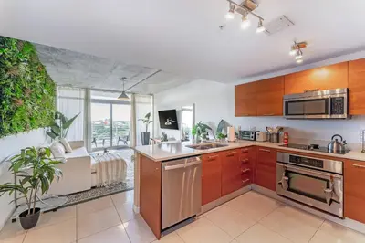 a kitchen with wooden cabinets and a large window at 1BR Miami Retreat with BBQ, Pool, & Skyline Views in Miami