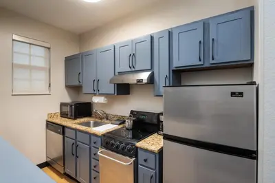 a kitchen with blue cabinets and a stainless steel refrigerator at Candlewood Suites Miami - Doral by IHG in Tamiami