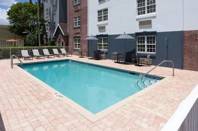 a swimming pool with chairs and a building at Candlewood Suites Miami - Doral by IHG in Tamiami