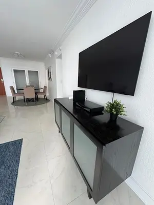 a living room with a large flat screen tv on a wall at 1 bedroom with amazing ocean view in Hollywood