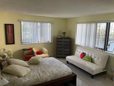 a bedroom with a bed and a couch and windows at Golden Isles Suite 315 in Hallandale Beach