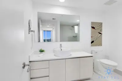 a white bathroom with a sink and a mirror at Modern 1BR with Pool & Balcony in Hallandale Beach