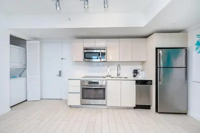 a kitchen with white cabinets and stainless steel appliances at Modern 1BR w- Kitchen on 30th Floor Epic Views in Hallandale Beach