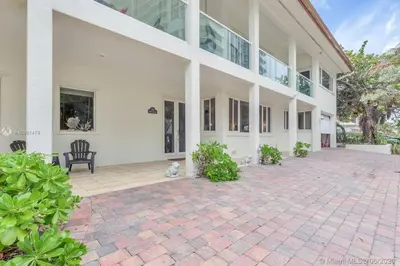 a large white building with a chair on a brick patio at One - BR spacious beach place in Hollywood