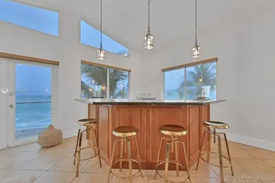 a kitchen with a island with bar stools at Oceanfront Villa On Semi-Private Holywood Beach in Hollywood