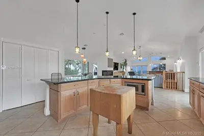 a large kitchen with wooden cabinets and a table at Oceanfront Villa On Semi-Private Holywood Beach in Hollywood