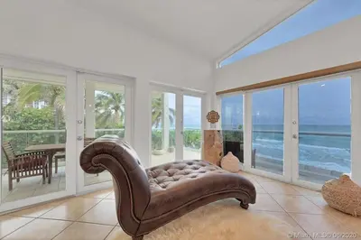 a living room with a leather chair and large windows at Oceanfront Villa On Semi-Private Holywood Beach in Hollywood