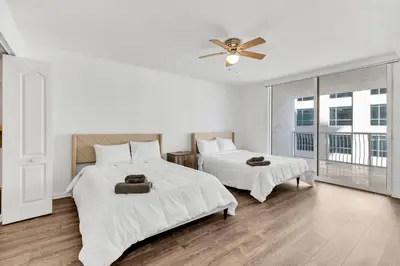 a white bedroom with two beds and a ceiling fan at Luxury Miami Brickell Stay-Bay View in Miami