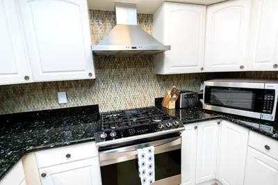 a kitchen with white cabinets and a stove and a microwave at The Aqua Villa in Hollywood