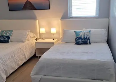 a white bedroom with two beds and two lamps at Luxury 3BR Duplex in Cutler Bay, Pool Table, BBQ, Terrace & Free Parking in Cutler Ridge