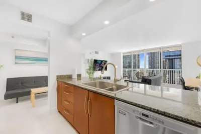 a kitchen with a sink and a living room at Modern Brickell Condo with Prime City Views in Miami