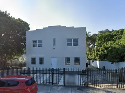 a white house with a red car parked in front of it at Stay Near Wynwood in Miami
