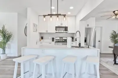a kitchen with white cabinets and white stools at Near Beach Family Escape Heated Pool Fire Pit BBQ in Hallandale Beach