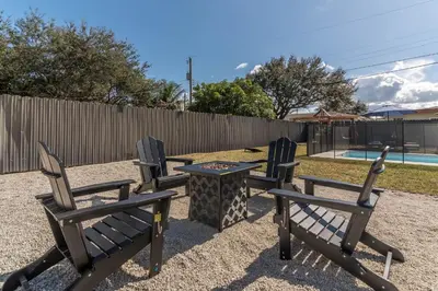 a group of chairs and a table in front of a fence at Near Beach Family Escape Heated Pool Fire Pit BBQ in Hallandale Beach