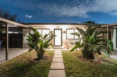 a house with two plants in the front yard at Near Beach Family Escape Heated Pool Fire Pit BBQ in Hallandale Beach