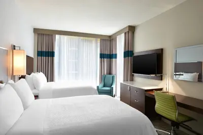 a hotel room with two beds and a desk and a television at Four Points by Sheraton Coral Gables in Miami