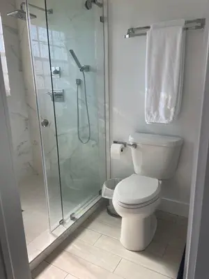 a bathroom with a toilet and a glass shower at Gardens Get Away in Pembroke Pines