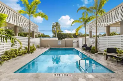 a swimming pool in the backyard of a house with palm trees at Resort-Style 1 Bed Condo with Pool Parking Rooftop & Gym in Hollywood