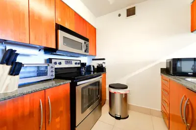 a kitchen with wooden cabinets and a stove and microwave at Condo That Will Make Feel the Ocean Breeze Close in Miami