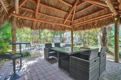 a patio with a table and chairs under a thatched roof at Tropical Oasis Studio w Pool in Fort Lauderdale