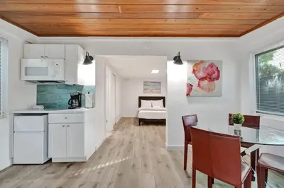 a kitchen with white cabinets and a table with chairs at Tropical Oasis Studio w Pool in Fort Lauderdale