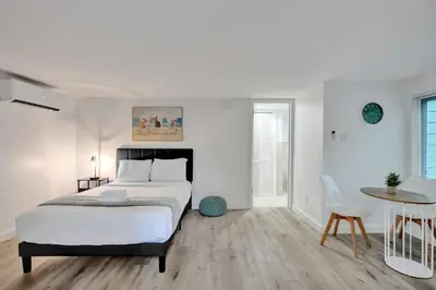 a white bedroom with a large bed and a table at Tropical Oasis Studio w Pool in Fort Lauderdale