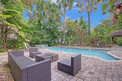 a swimming pool with wicker chairs and a table and a swimming pool at Tropical Oasis 2BR House w Pool in Fort Lauderdale