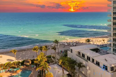 a view of the beach and the ocean at sunset at Stylish Ocean Apartment with Pool in Hollywood