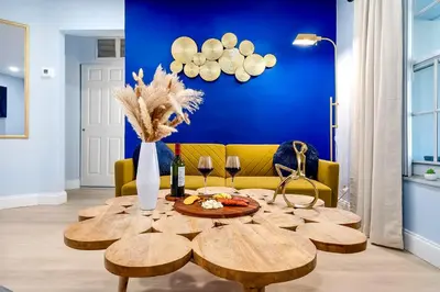 a living room with a table and a yellow couch at Las Olas Fort Lauderdale Getaway Pool, BBQ, Mini Golf & Game Room in Fort Lauderdale