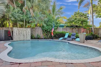 a swimming pool with two chairs and a fence at Kiki 5 - Men's Clothing optional Guest Houses in Fort Lauderdale