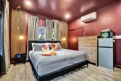 a bedroom with a bed with red walls and a refrigerator at Kiki 5 - Men's Clothing optional Guest Houses in Fort Lauderdale