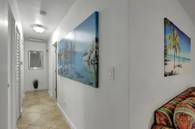 a hallway with three paintings on the wall at Relaxing Retreat 2BR Oasis with Pool and Outdoor BBQ in Pembroke Pines