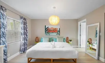 a bedroom with a large white bed and a chandelier at Sunny Cottage in Fort Lauderdale