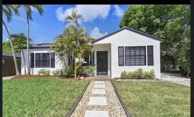 a white house with a palm tree in a yard at Sunny Cottage in Fort Lauderdale