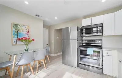 a kitchen with a table and a stainless steel refrigerator at Sunny Cottage in Fort Lauderdale