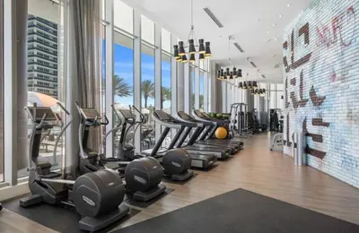 a gym with rows of treadmills and elliptical machines at Level Up in This Condo w Breathtaking Views! in Hollywood
