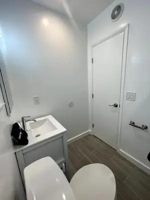 a white bathroom with a toilet and a sink at Tranquil Studio W Parking 10 min to Beach FLL in Hollywood