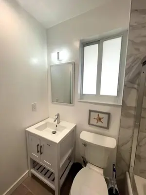 a bathroom with a toilet and a sink and a window at Las Olas Studio W Parking 10 min to FLL and beach in Hollywood