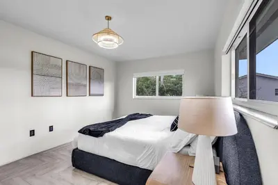 a white bedroom with a bed and a lamp at Pickleball fun Family home near Hard Rock Stadium in North Miami