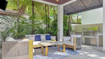 a patio with a couch and a table and a kitchen at Lux 4BR Retreat with Heated Pool, BBQ, and Bikes in Miami