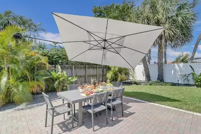 a table and chairs with a white umbrella at The Zen Den - Heated pool - One mile to heart of The Drive in Fort Lauderdale