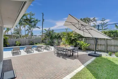 a patio with a table and chairs and an umbrella at The Zen Den - Heated pool - One mile to heart of The Drive in Fort Lauderdale